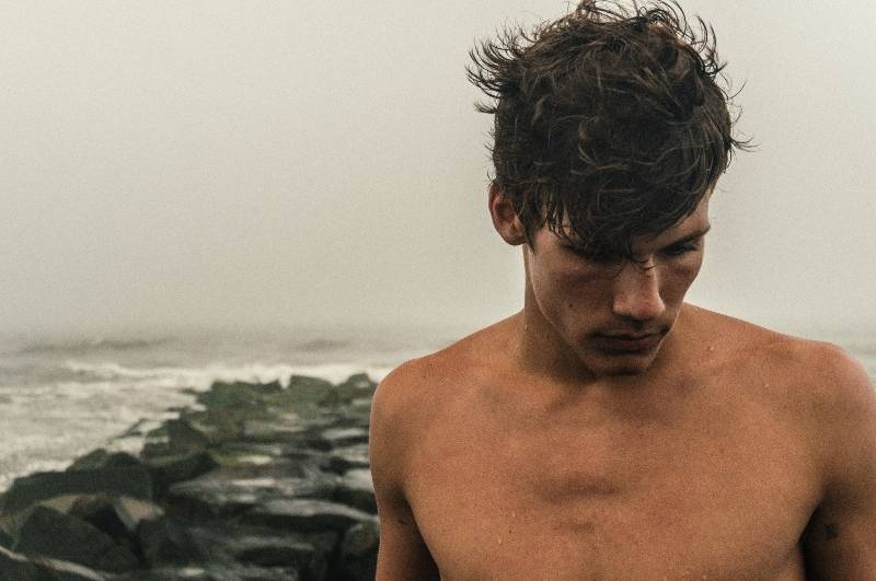 Shirtless man with wet hair on a beach