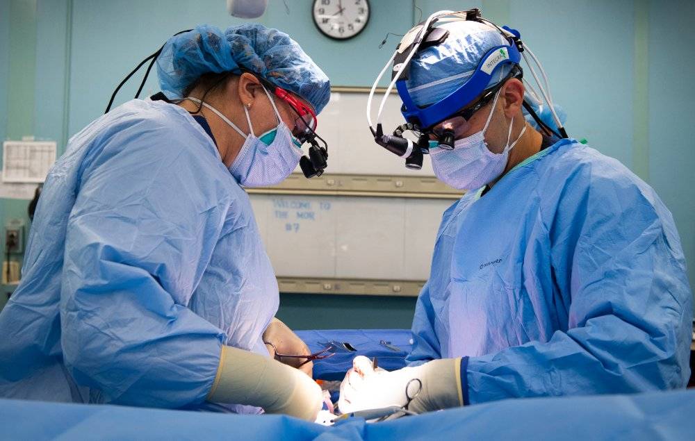 Two doctors performing breast augmentation surgery.