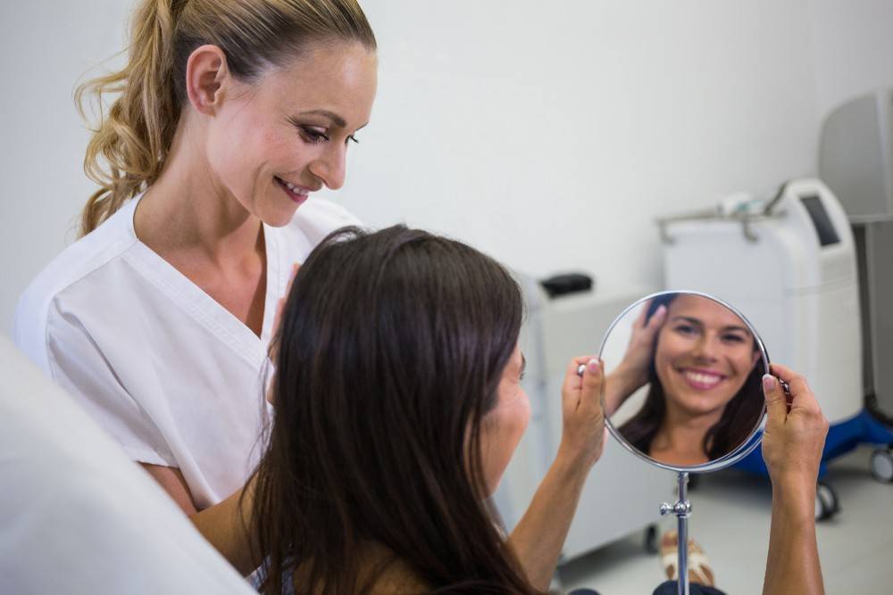 Mujer revisando su piel en el espejo después de su cirugia plastica en mexico