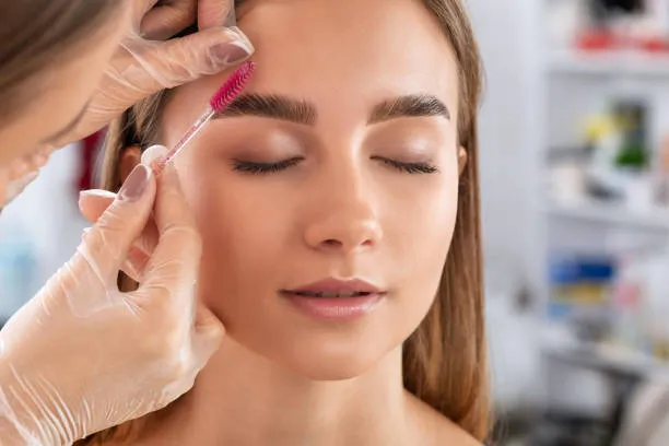Doctor styling a woman's eyebrows while discussing the benefits of microblading vs eyebrow implant for lasting results