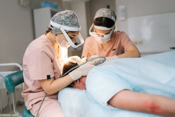 Two doctors working together to perform FUE hair transplant, carefully implanting hair grafts to restore the patient’s hairline and density.