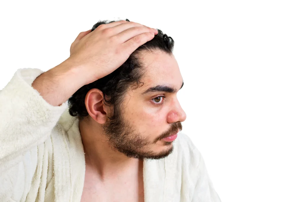 Doctor in blue gloves examines a man's thinning hair and receding hairline, addressing "why am I losing so much hair?".