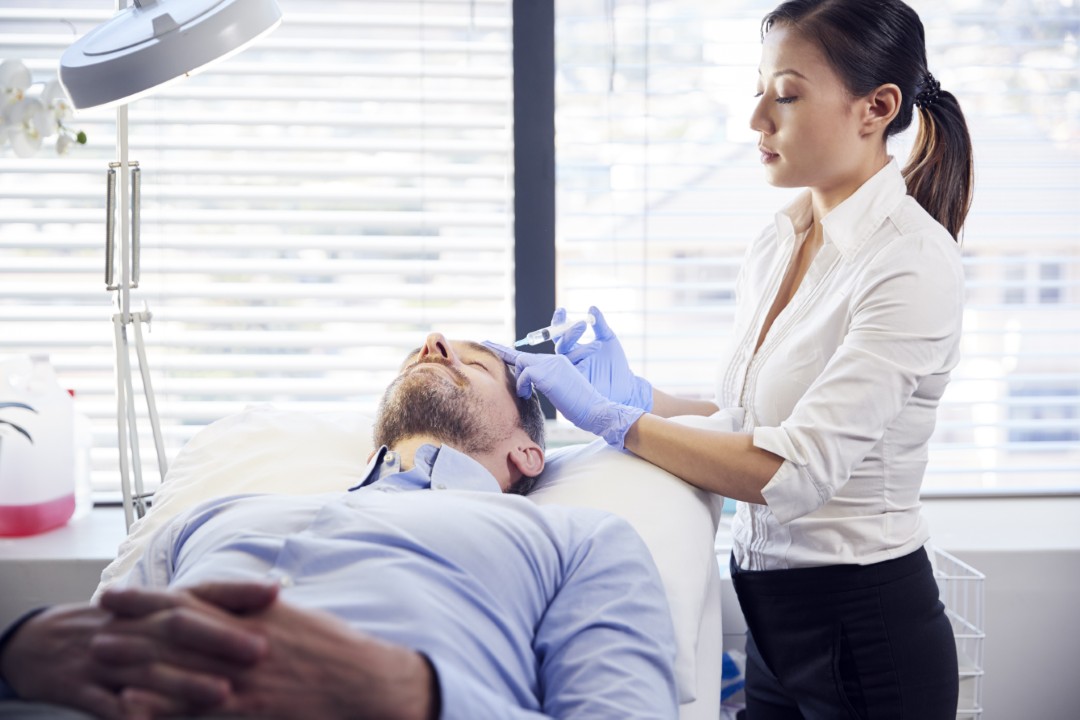 Female doctor performing a scalp injection at a hair transplant clinic.