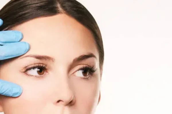 Woman in a consultation session where her eyebrows are examined in preparation for a facial hair transplant focused on brow restoration.
